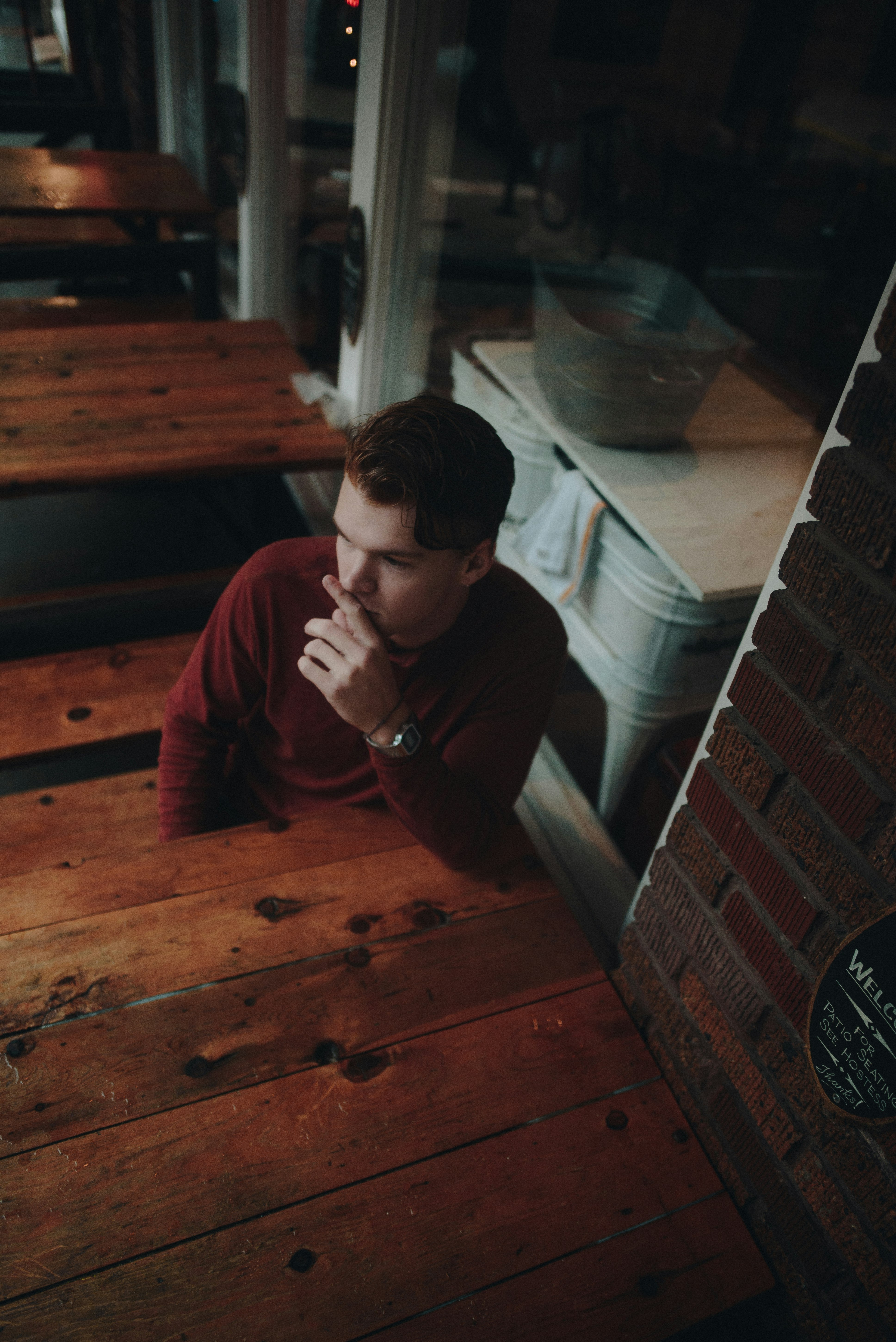 man sitting on brown wooden bench